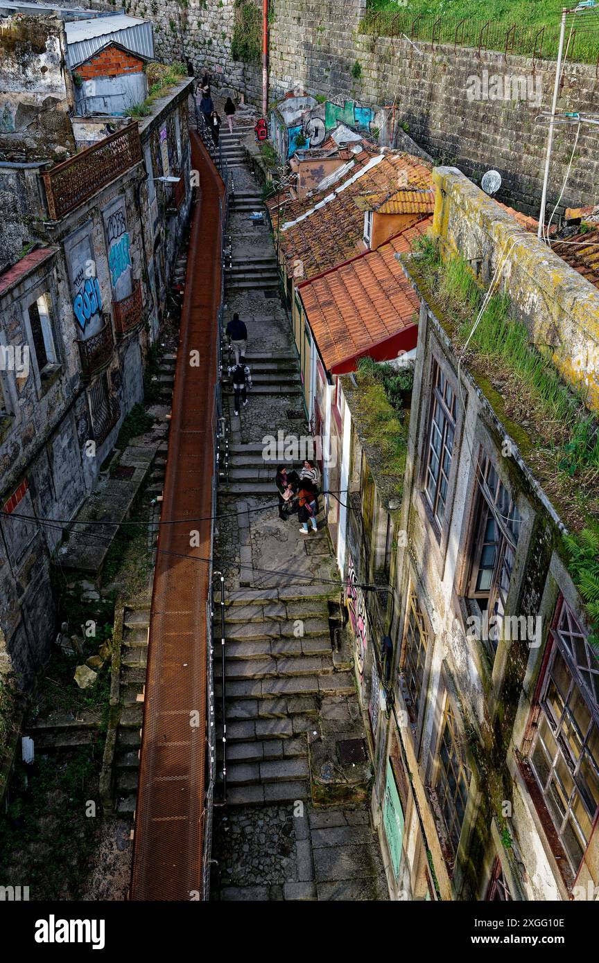Eine schmale Treppe in Porto, flankiert von verwitterten Gebäuden und lebendiger Straßenkunst, führt durch einen historischen und stimmungsvollen Teil der Stadt Stockfoto