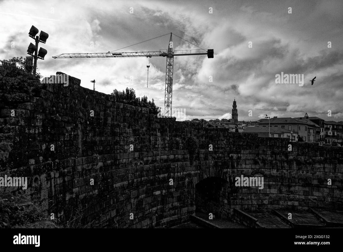 Der Baukran erhebt sich über die alten Steinmauern in Porto und verbindet die historische Vergangenheit der Stadt mit der laufenden Entwicklung Stockfoto