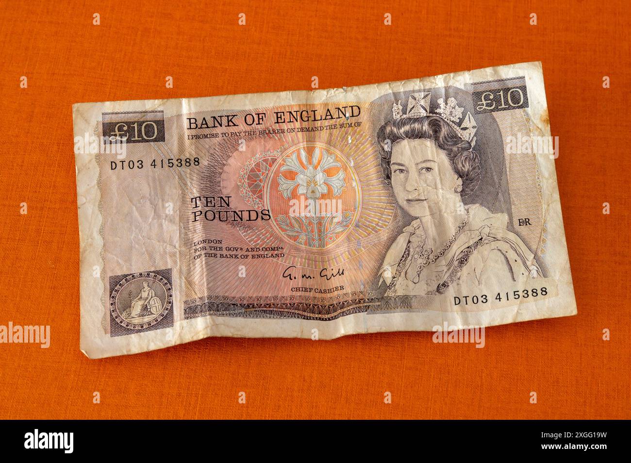 Die alte 10-Pfund-Banknote liegt auf einem orangefarbenen Hintergrund Stockfoto