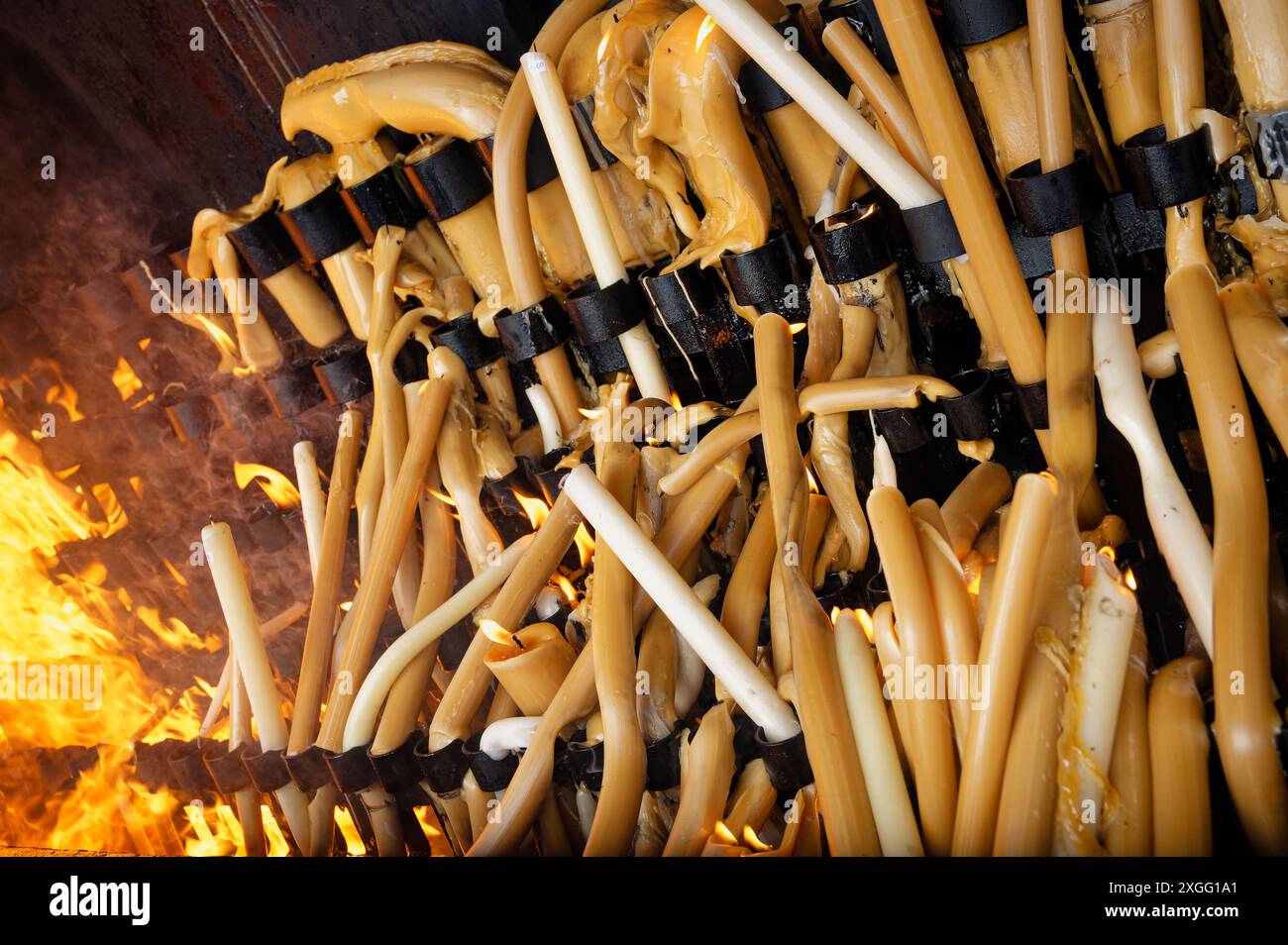 Kerzen schmelzen und brennen in Metallhaltern an der religiösen Stätte von Fátima Stockfoto