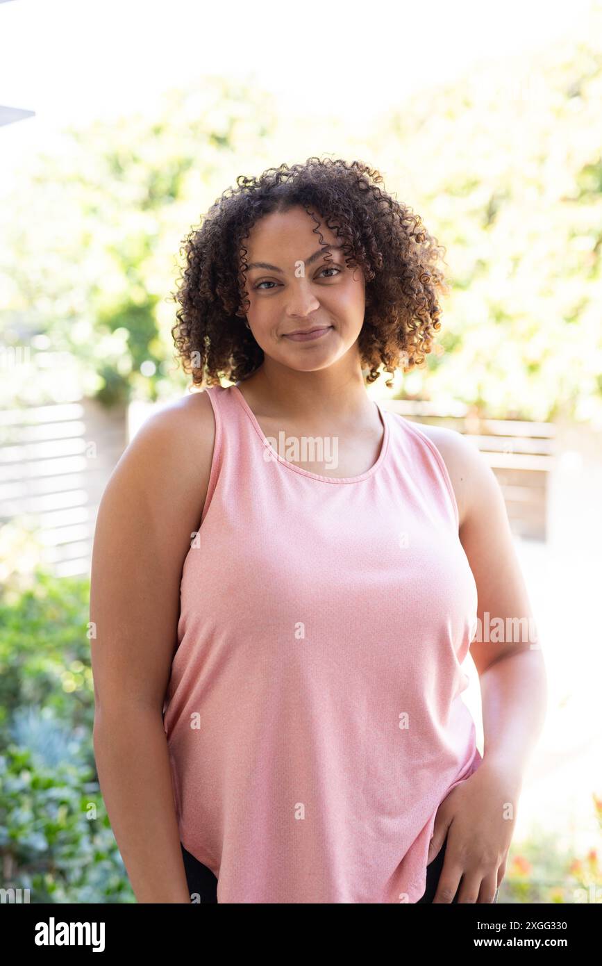 Lächelnde Frau in rosa Spitze steht draußen und genießt den sonnigen Tag Stockfoto