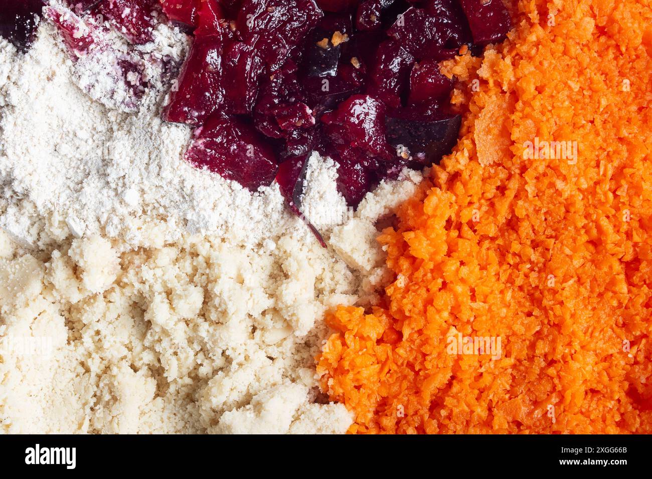 Eine Nahaufnahme von vier verschiedenen Zutaten nebeneinander: hafermehl, gemahlene Mandeln, gehackte Pflaume und geriebene Karotten. Die lebendigen Farben und der abwechslungsreiche Text Stockfoto