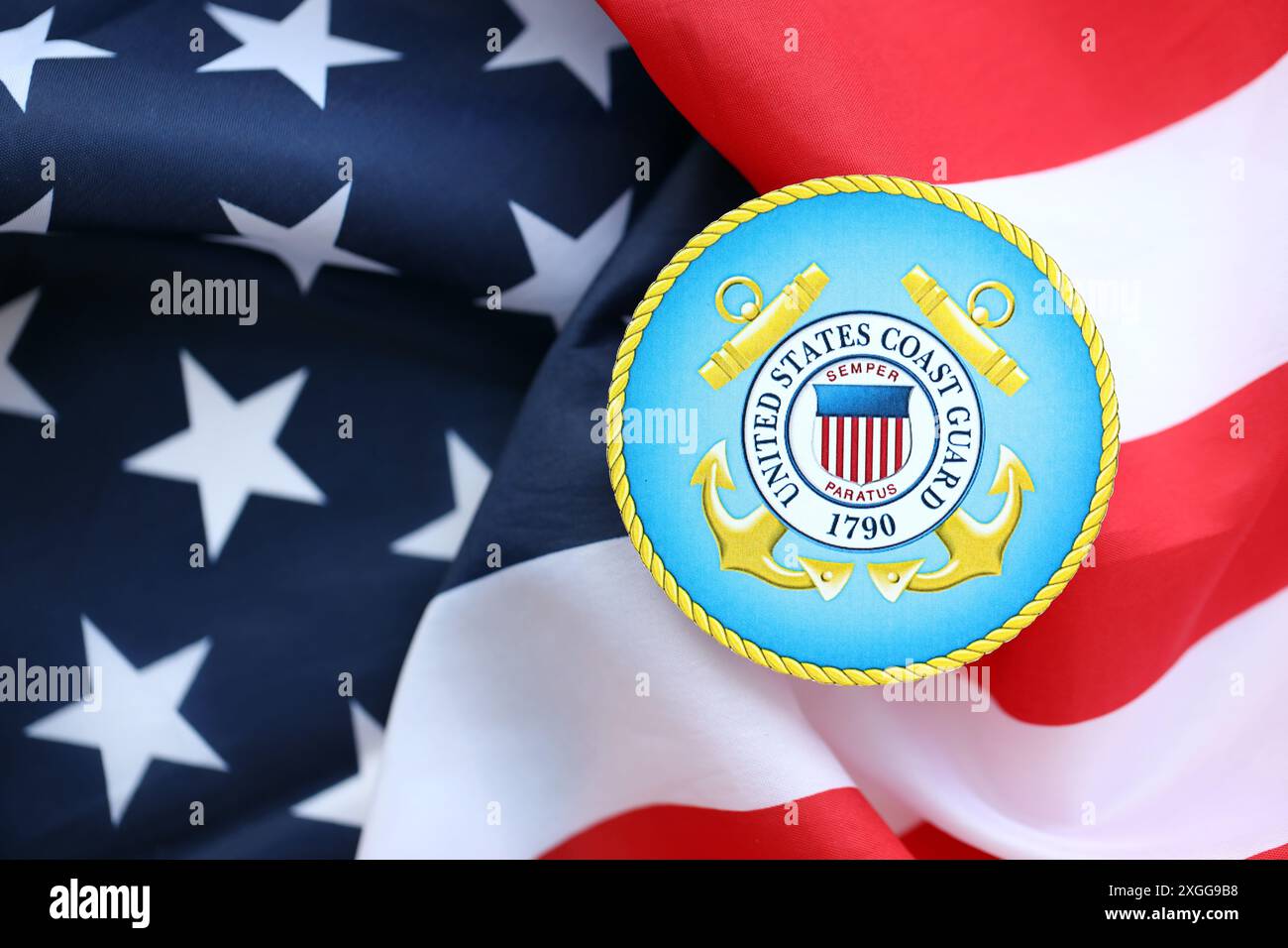 KIEW, UKRAINE - 26. JUNI 2024 Wappenaufkleber der US-Küstenwache auf gefalteter US-Flagge in Nahaufnahme Stockfoto