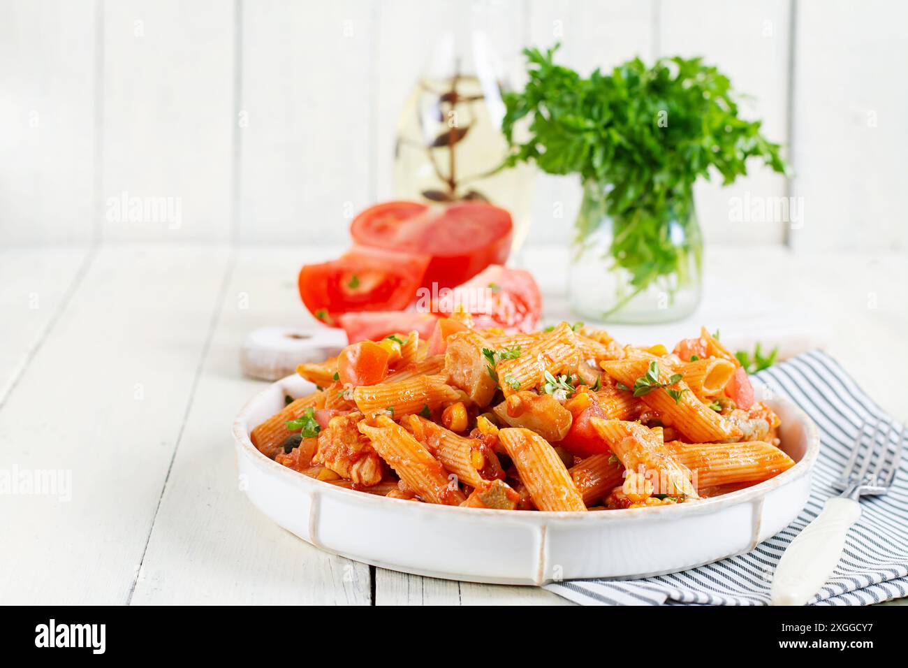 Klassische italienische Pasta Penne Arrabbiata mit Gemüse auf weißem Holztisch. Penne Pasta mit Sauce Arrabbiata. Stockfoto