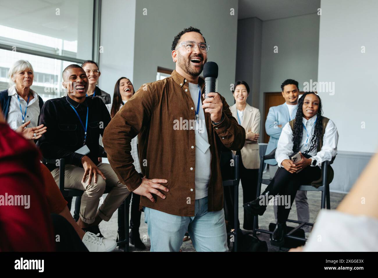 Ein Referent, der ein begeistertes Publikum während eines Geschäftsseminars in einem hellen, modernen Konferenzraum anspricht. Stockfoto