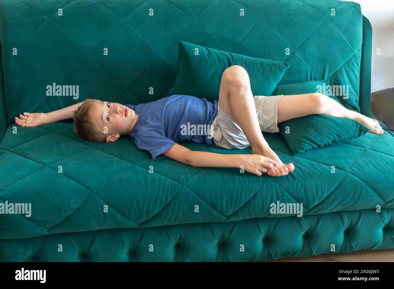 Der Junge liegt auf der Couch, faulenzt herum und entspannt sich. Stockfoto