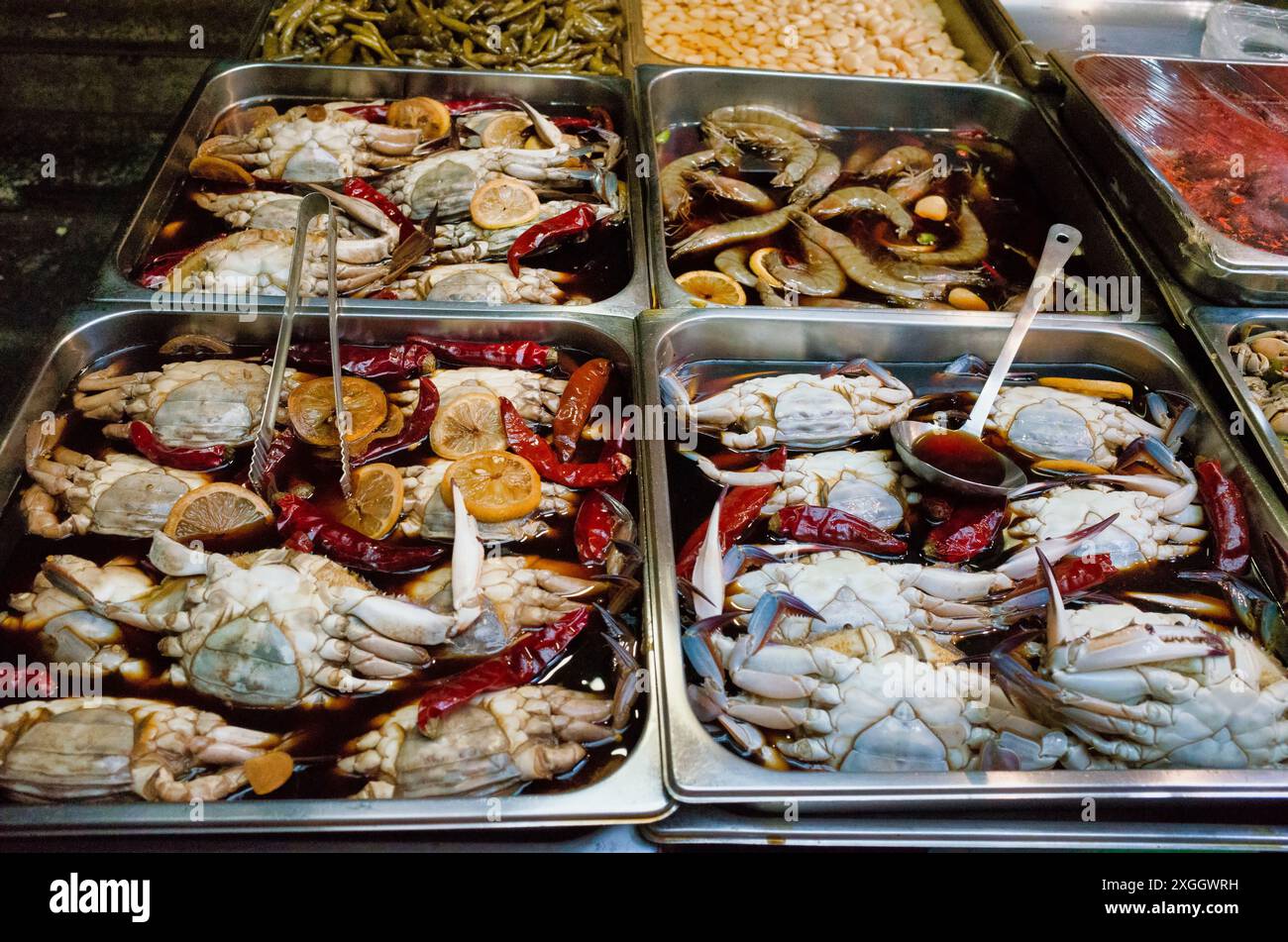 Frisch zubereitete Krabben und Meeresfrüchte in Soße, ausgestellt auf Metalltabletts auf einem Markt Stockfoto