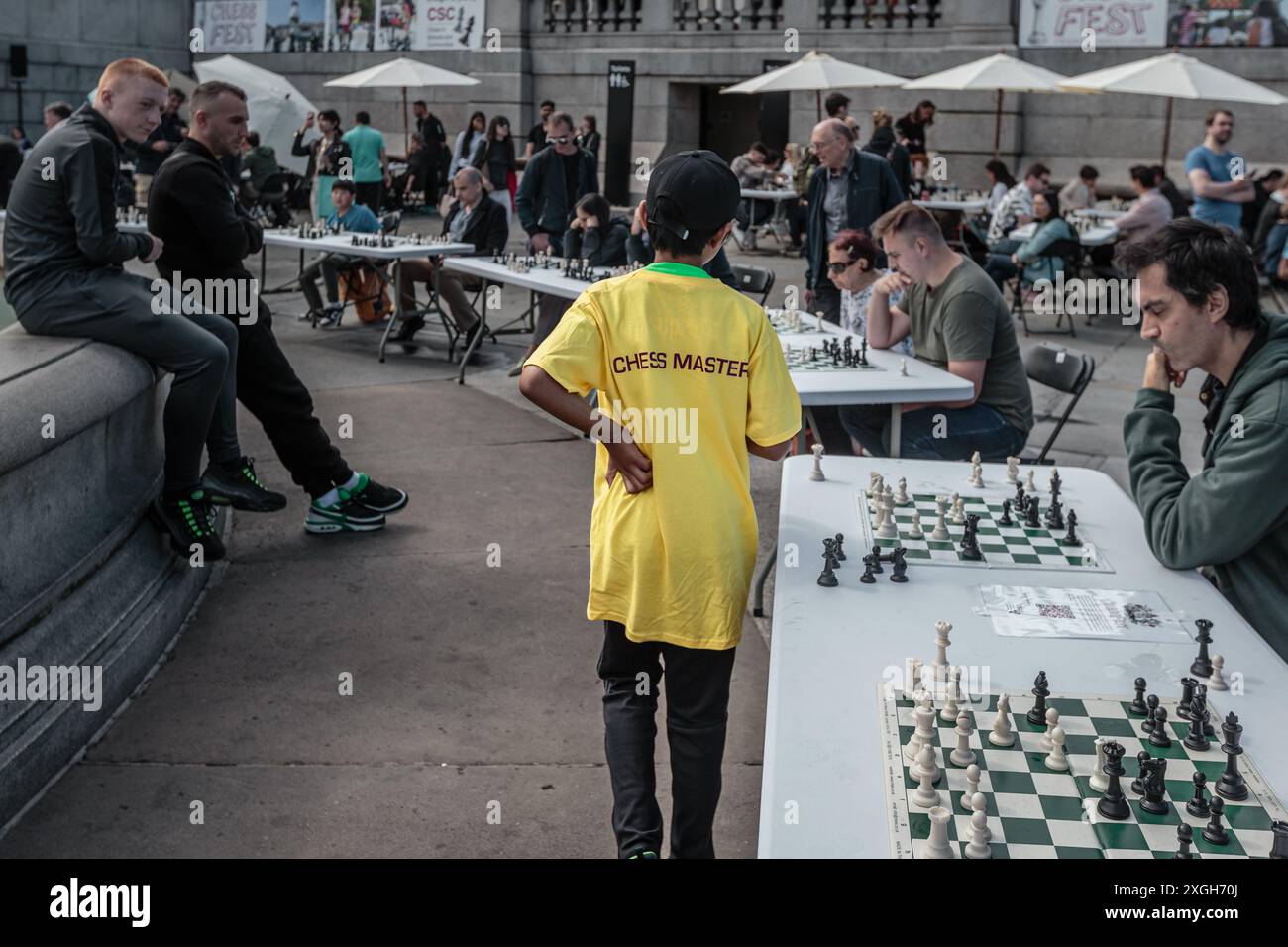 Ein junger Schachmeister nimmt mehrere Spieler auf dem Schachspiel in Schulen und Gemeinschaften (CSC) in London auf. Stockfoto