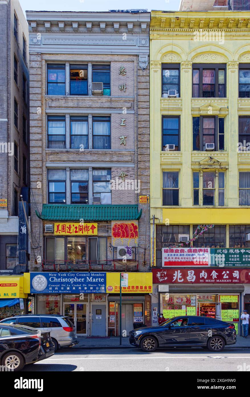 NYC Chinatown: 65 East Broadway, ein fünfstöckiges Backsteingebäude, das „chinesisch“ gemacht wurde, indem über dem zweiten Stock ein grüner Fliesengesims hinzugefügt wurde. Stockfoto