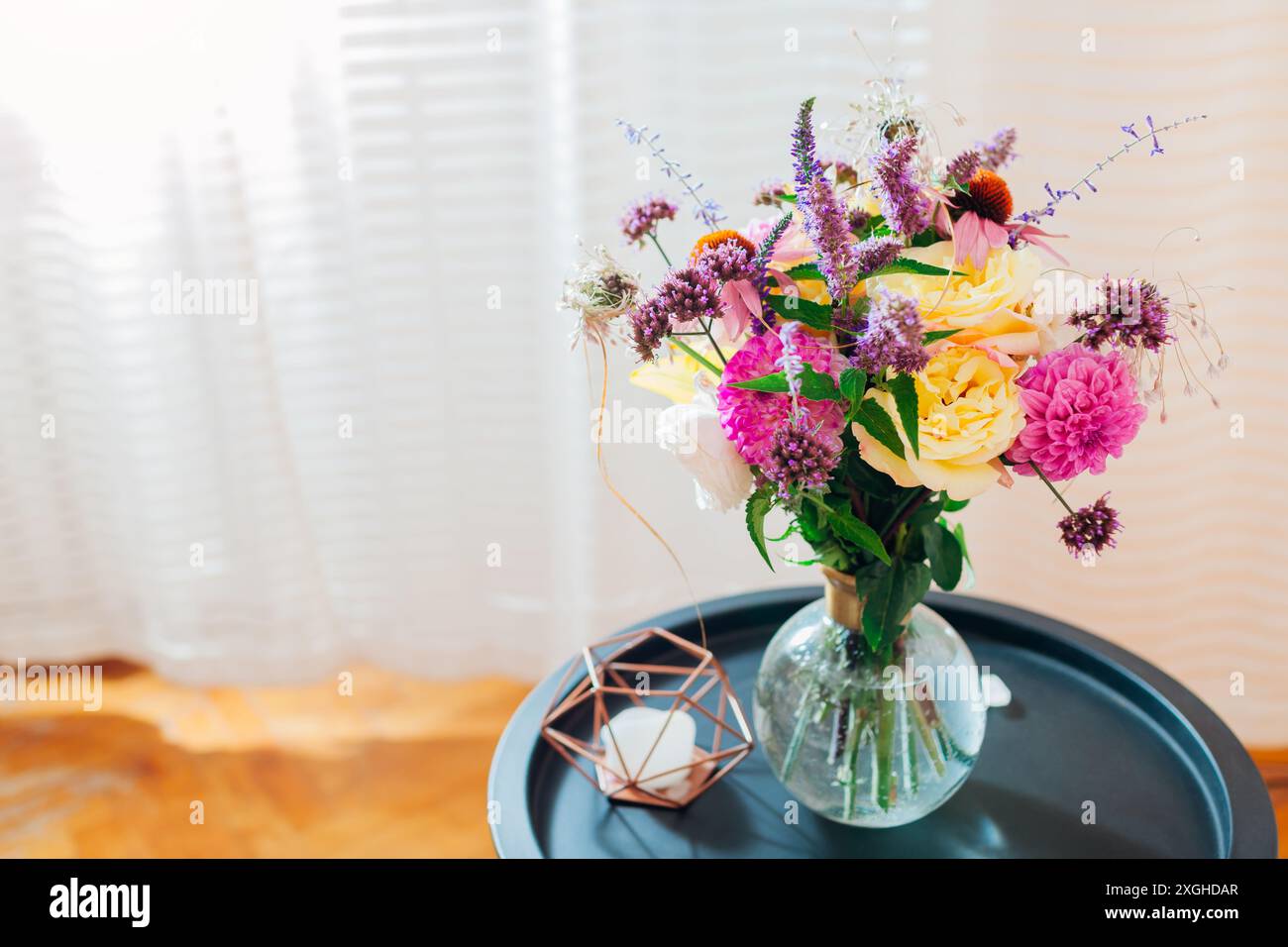 Blick von oben auf den frischen Sommerstrauß in transparenter Vase auf dem Tisch. Rosa, gelbe, lila Blüten. Blumenarrangements zu Hause aus Dahlien, Rosen, ver Stockfoto