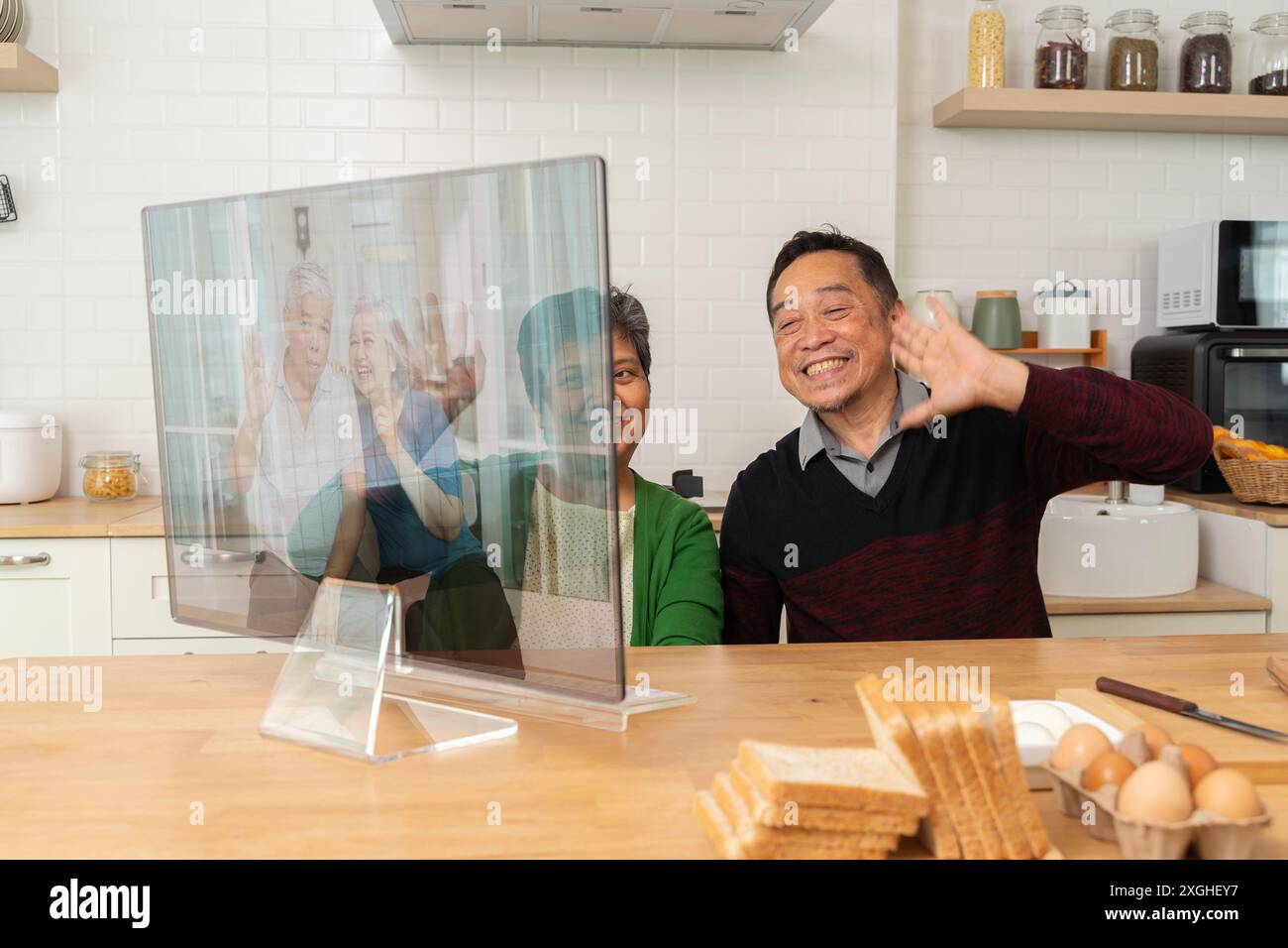 Großeltern am Computer kommunizieren mit Enkelkindern per Video-Chat von der Küche zu Hause, Urlaub Aktivitäten für pensionierte Paare, Seniorengesundheitspflege und Stockfoto