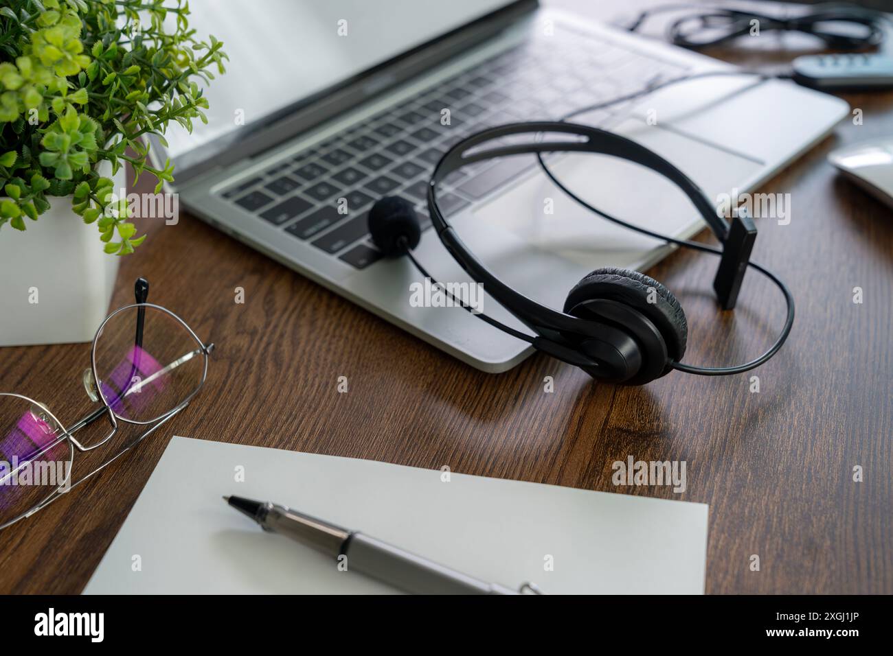 Kopfhörer, die für ein Online-Meeting mit einem Laptop verbunden sind, werden während der Pause beiseite gelegt. Stockfoto