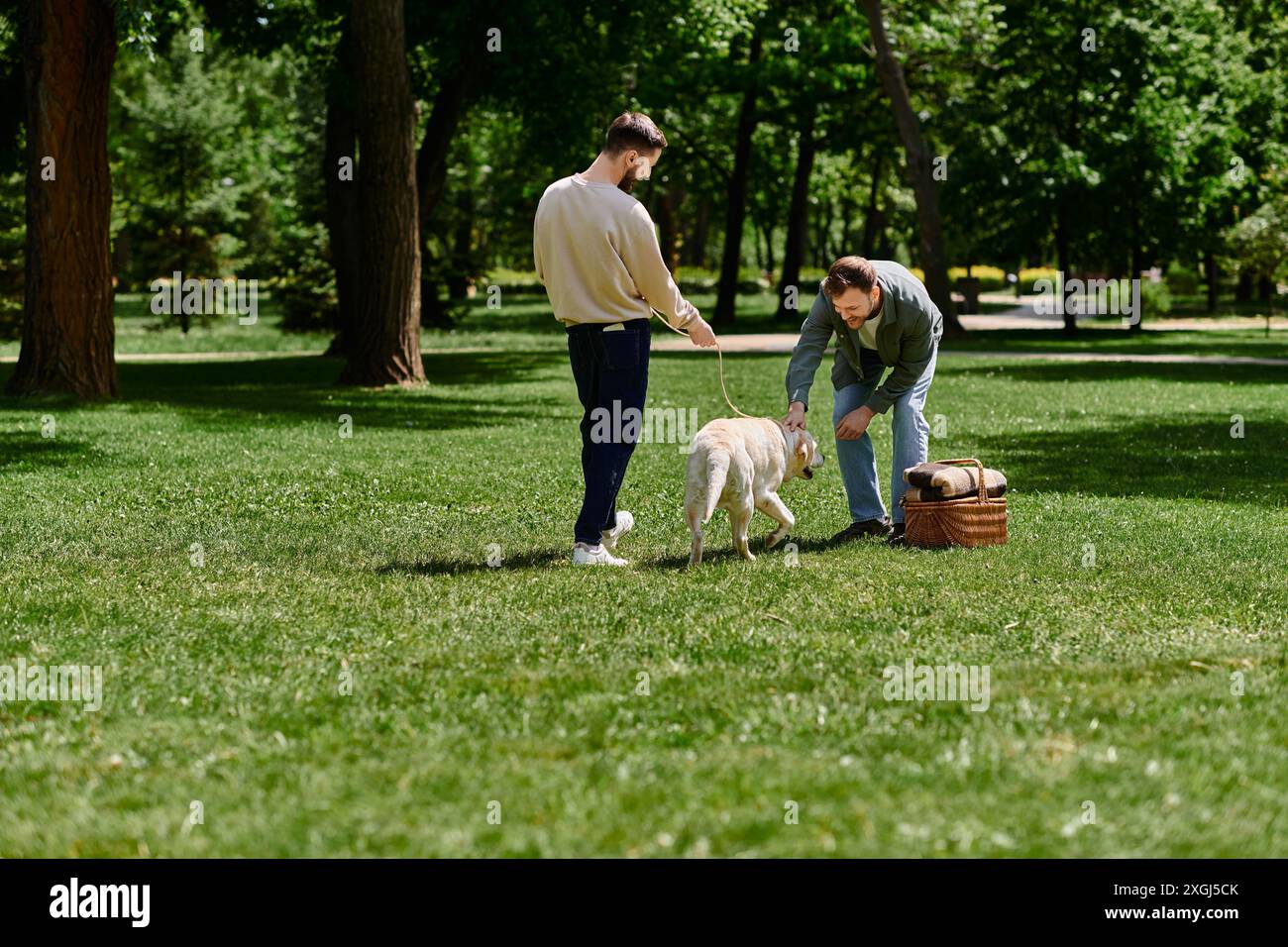 Ein schwules Paar mit Bärten genießt einen sonnigen Nachmittag in einem Park mit ihrem labrador-Hund. Stockfoto