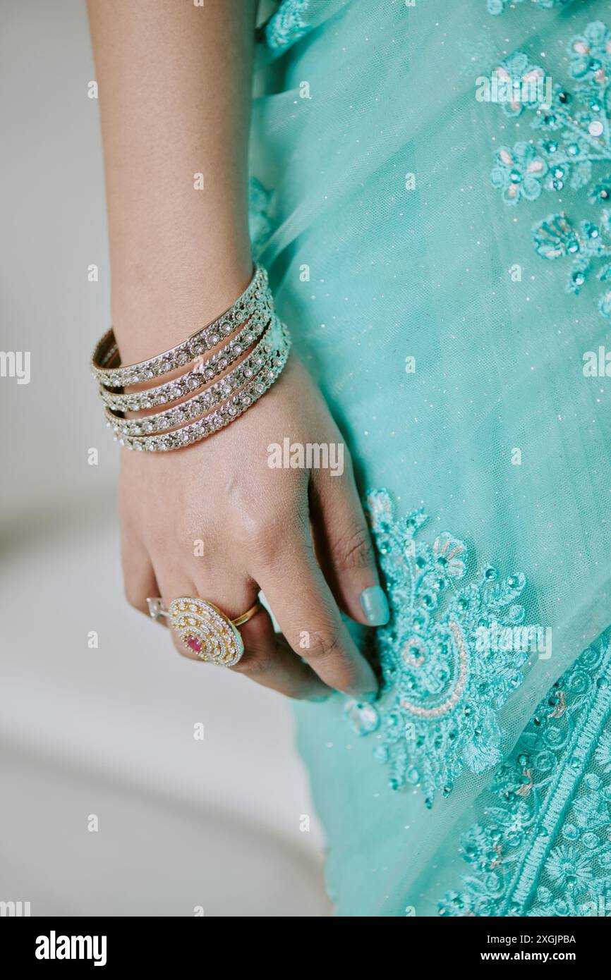 Damenhand mit Diamantringen und türkisfarbenem Kleid am Armband Stockfoto
