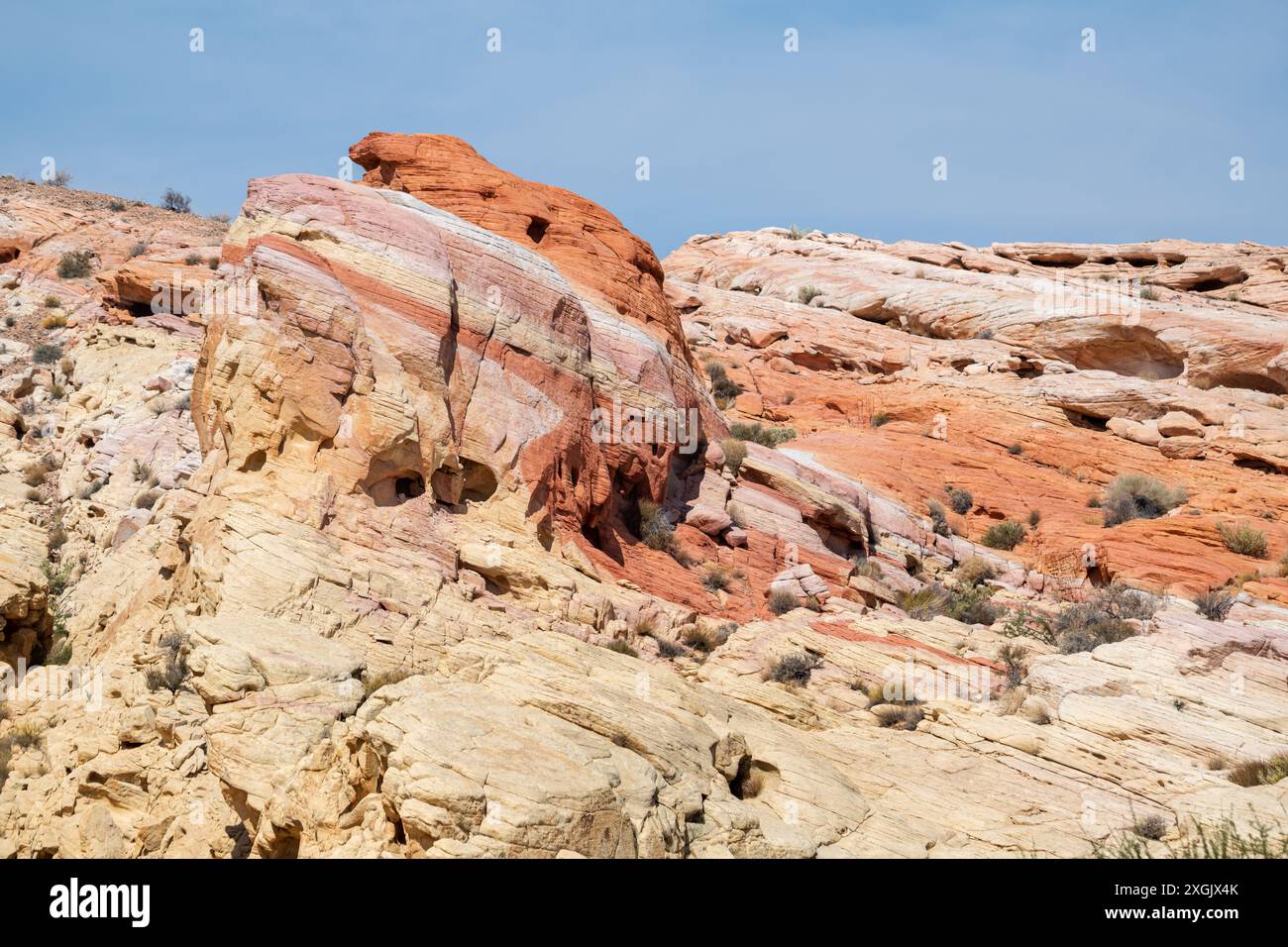 Ein felsiger Hügel mit einem großen Felsen in der Mitte. Der Fels ist eine Mischung aus roten, gelben und braunen Farben Stockfoto