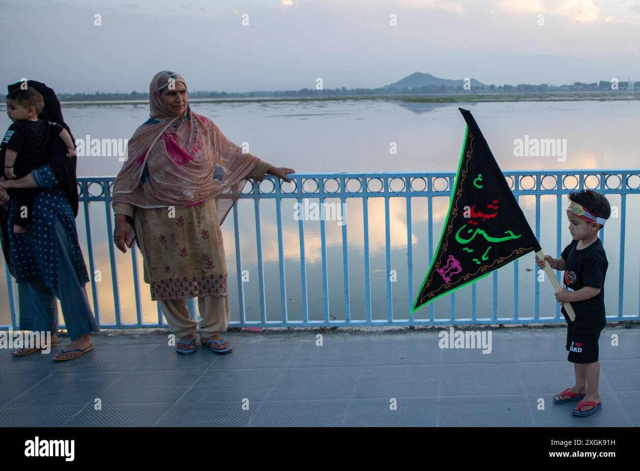 Srinagar, Indien. Juli 2024. Ein schiitischer muslimischer Junge aus Kaschmir hält eine islamische Flagge an der Uferstraße in Srinagar. Muharram ist der erste Monat des islamischen Kalenders. Es ist einer der heiligsten Monate im islamischen Kalender. Schiitische Muslime gedenken Muharram als einen Monat der Trauer zum Gedenken an das Martyrium des islamischen Propheten Muhammads Enkel Imam Hussain, der 680 n. Chr. in der Schlacht von Karbala auf Ashura (10. Tag Muharram) getötet wurde (Foto: Faisal Bashir/SOPA Images/SIPA USA) Credit: SIPA USA/Alamy Live News Stockfoto