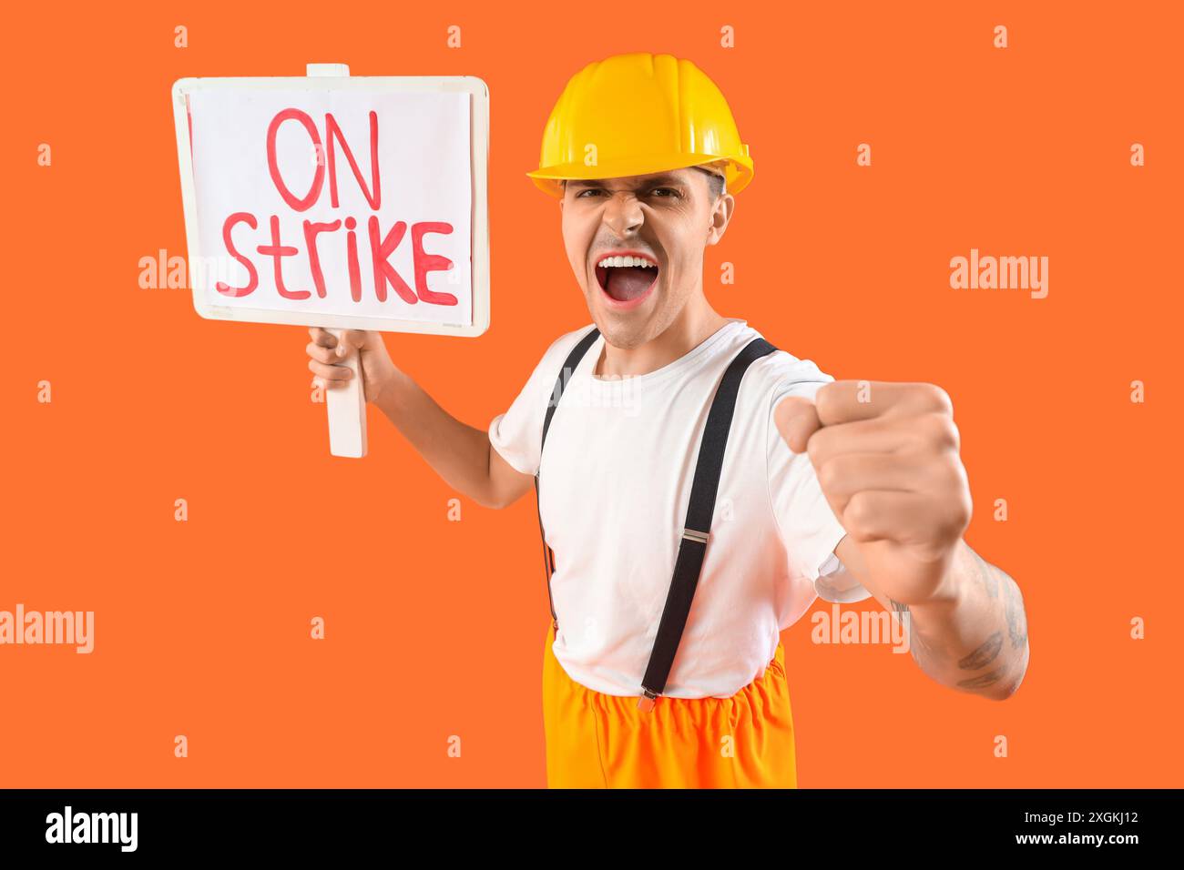 Protest gegen die Feuerwehr mit Plakat mit STREIKTEXT vor orangem Hintergrund Stockfoto