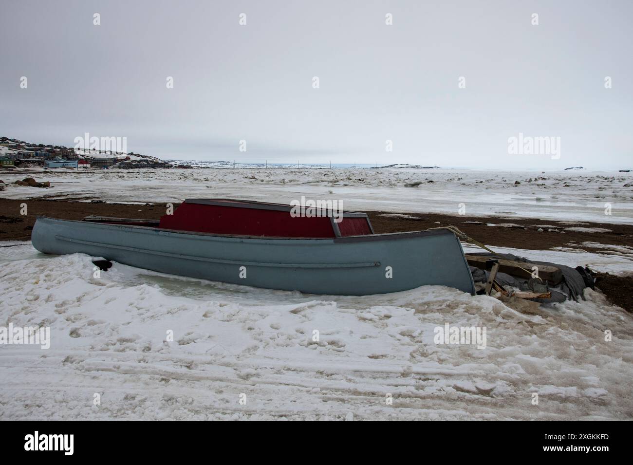 Graues und rotes Holzboot am Strand der Frobisher Bay in Iqaluit, Nunavut, Kanada Stockfoto