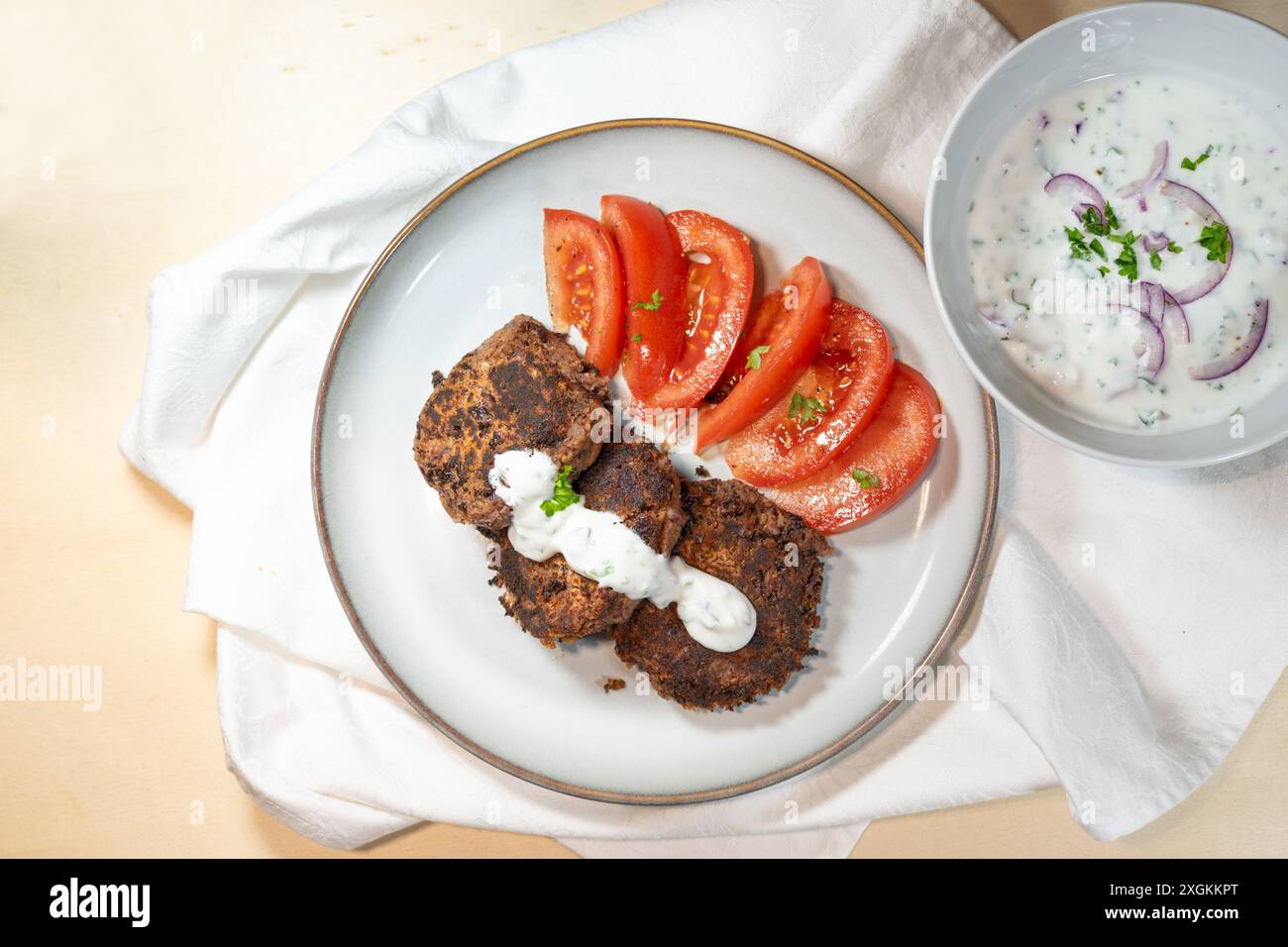 Vegetarische Pasteten aus roten Kidneybohnen mit Tomaten und einem Joghurtdip auf einem Teller, gesunde Mahlzeit mit viel Protein und Ballaststoffen, High ang Stockfoto
