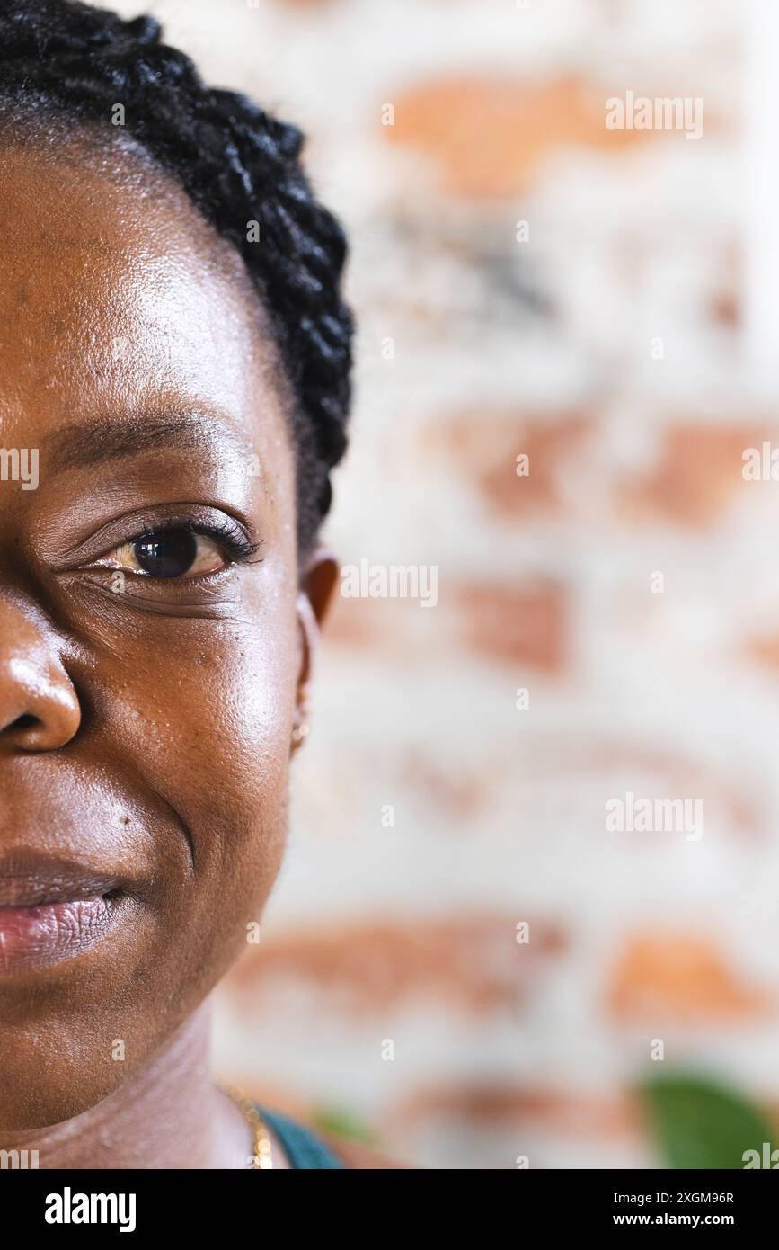 Nahaufnahme einer starken und fitten afroamerikanischen Frau drinnen, mit Kopierraum. Ihr Ausdruck ist ruhig und der Hintergrund ist unaltere gemauerte Mauer Stockfoto