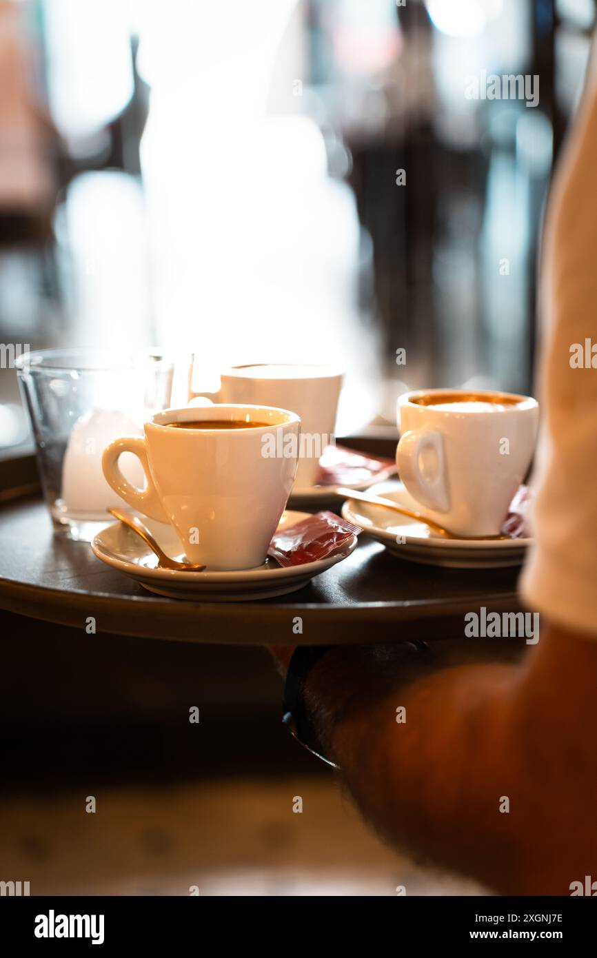 Nahaufnahme eines Tabletts mit Kaffee, der von einem Kellner beim Frühstück gehalten wird. Vertikal Stockfoto