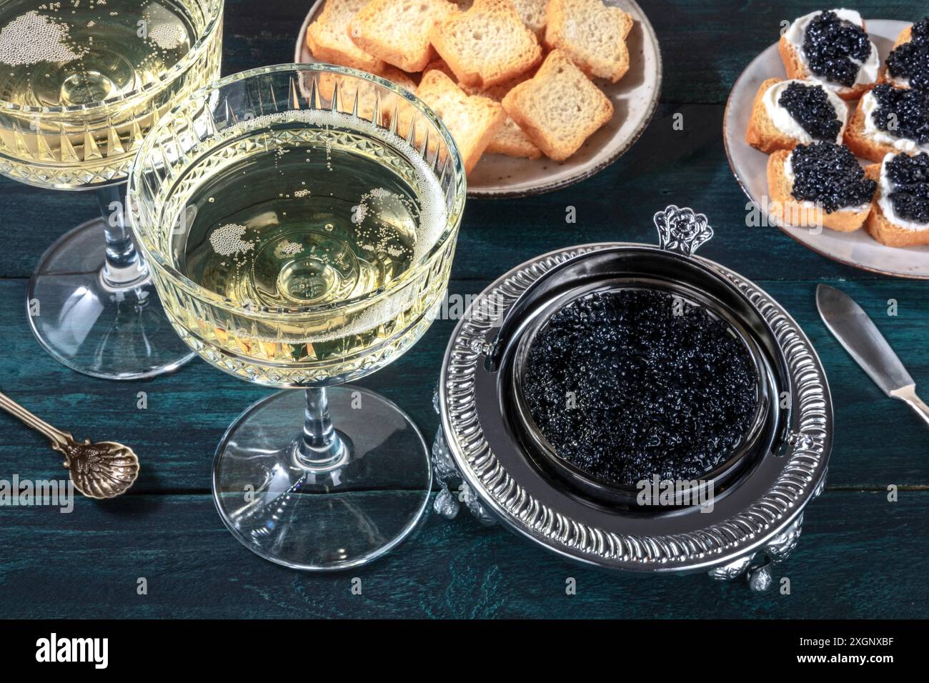 Kaviar und Champagner im Vintage-Stil mit Brot und Toast auf dunkelblauem Holzhintergrund Stockfoto