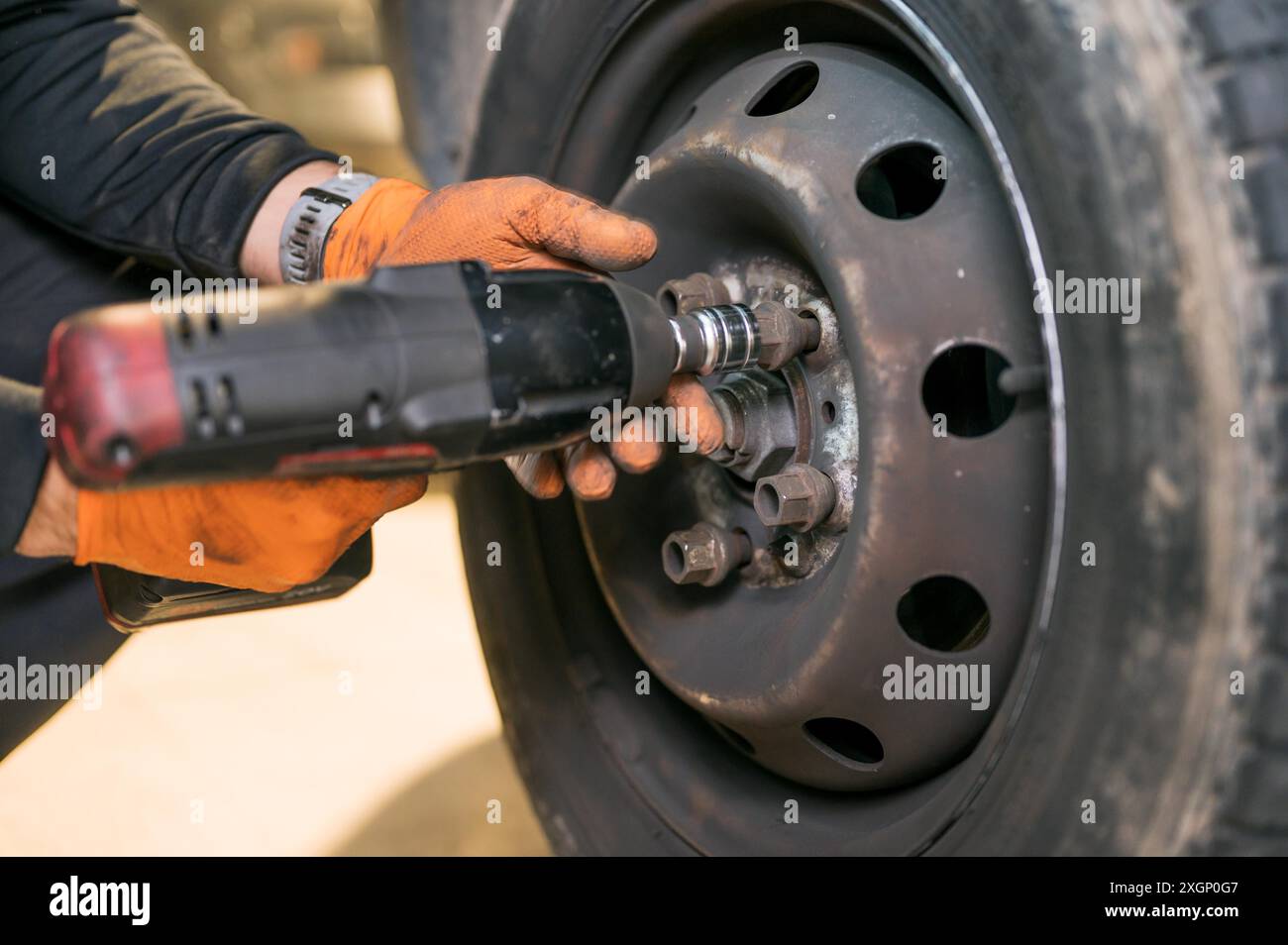 Kfz-Mechaniker Arbeiter tun Reifen oder Rad Austausch mit Elektroschlüssel in der Garage der Reparatur-Service-Station. Hochwertige Fotos Stockfoto