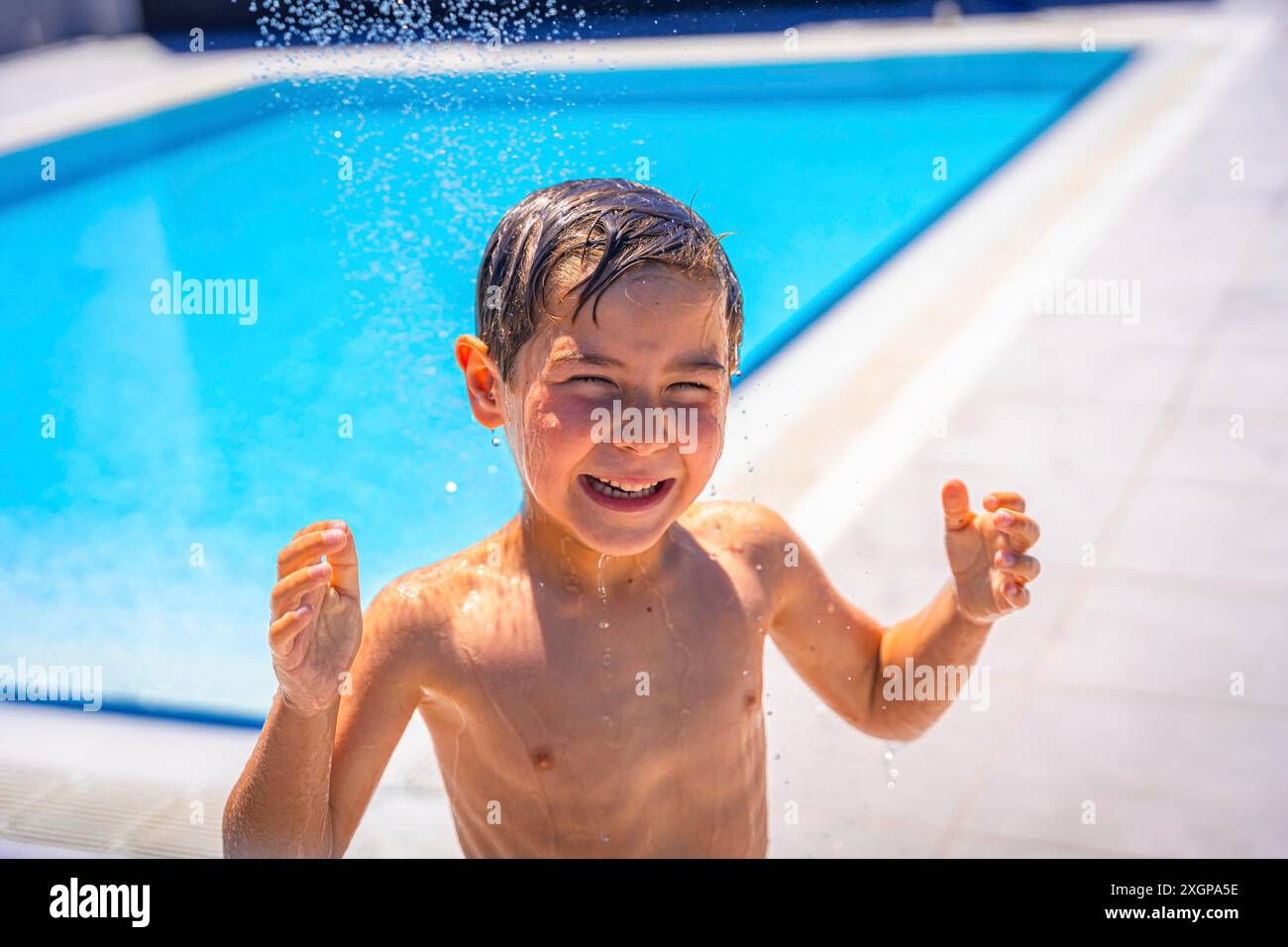 Porträt eines kaukasischen nassen Jungen, der allein im Pool spielt Stockfoto