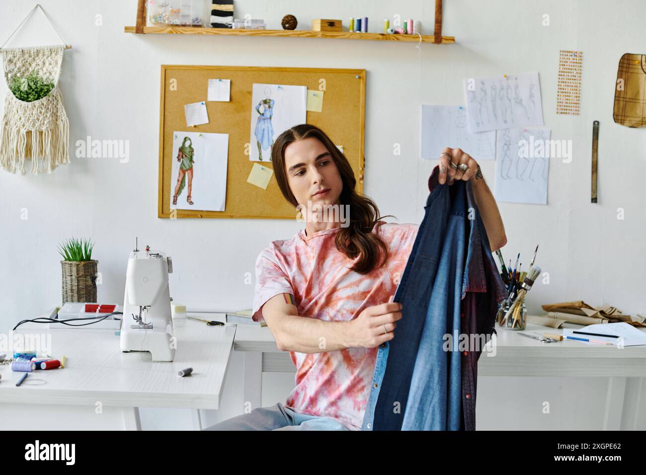 Ein junger Mann untersucht in seinem Heimwerkerwerkeratelier entsorgte Kleidung. Stockfoto