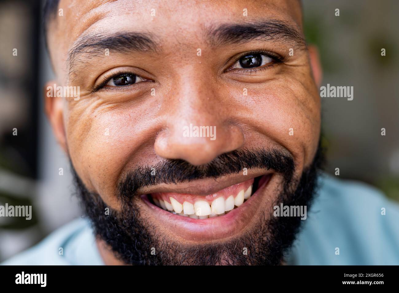 Nahaufnahme eines jungen, birassischen Mannes, der in die Kamera lächelt. Sein fröhlicher, unveränderter Ausdruck verleiht dem Bild eine warme, persönliche Note. Stockfoto