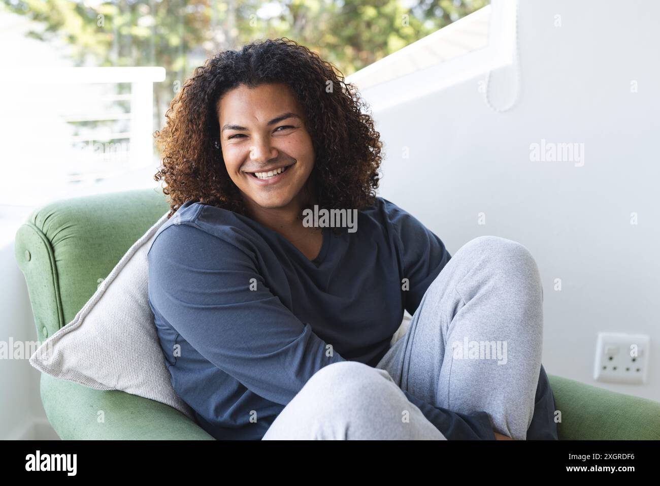 Junge, birassische Männer loungieren bequem zu Hause, mit Kopierraum. Er verströmt eine entspannte und fröhliche Atmosphäre in einer ungezwungenen Umgebung. Stockfoto