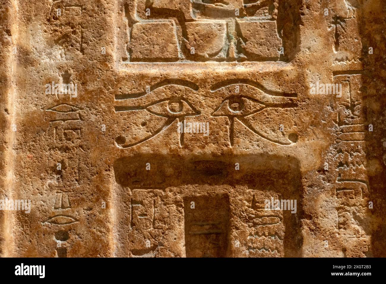 Altes ägyptisches Steinmauerfragment mit geschnitzten Augen-Symbolen Stockfoto