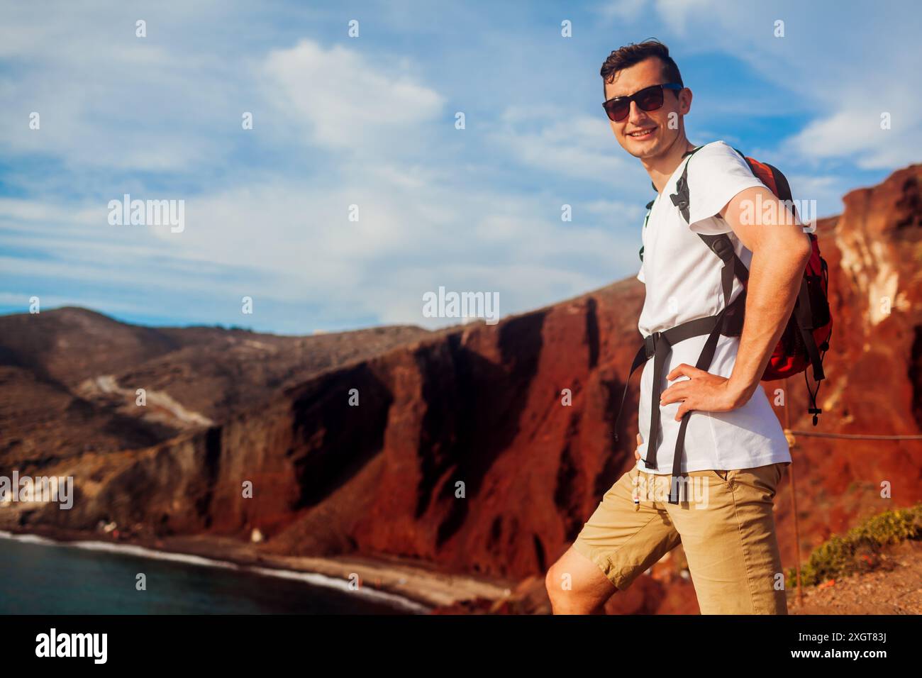 Tourist genießt Roten Strand, Blick auf die Küstenlandschaft auf Santorin Insel, Griechenland. Mann Rucksacktouristen reisen während der Sommerferien Stockfoto Tourist genießt Roten Strand, Blick auf die Küstenlandschaft auf Santorin Insel, Griechenland. Mann Rucksacktouristen reisen während der Sommerferien Stockfoto