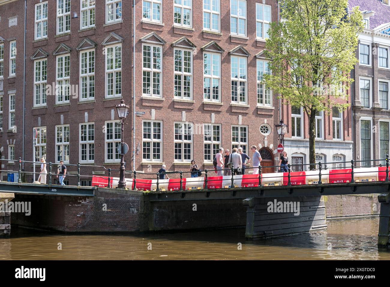 Die Menschen versammeln sich an einem sonnigen Tag an einem Kanal in Amsterdam, den Niederlanden. Stockfoto