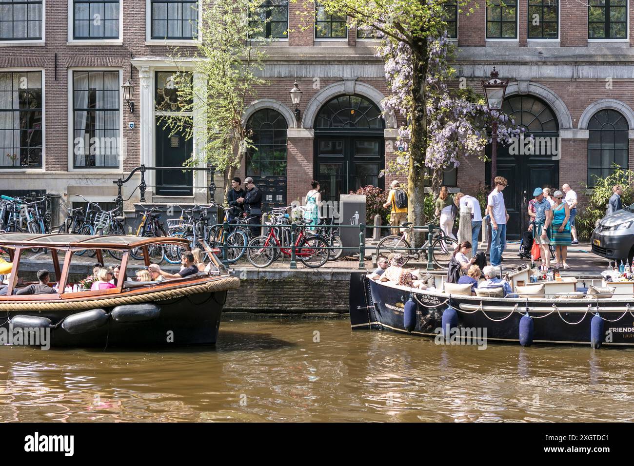 Menschen auf Sportbooten genießen die Kanäle an einem sonnigen Tag in Amsterdam, Niederlande. Stockfoto