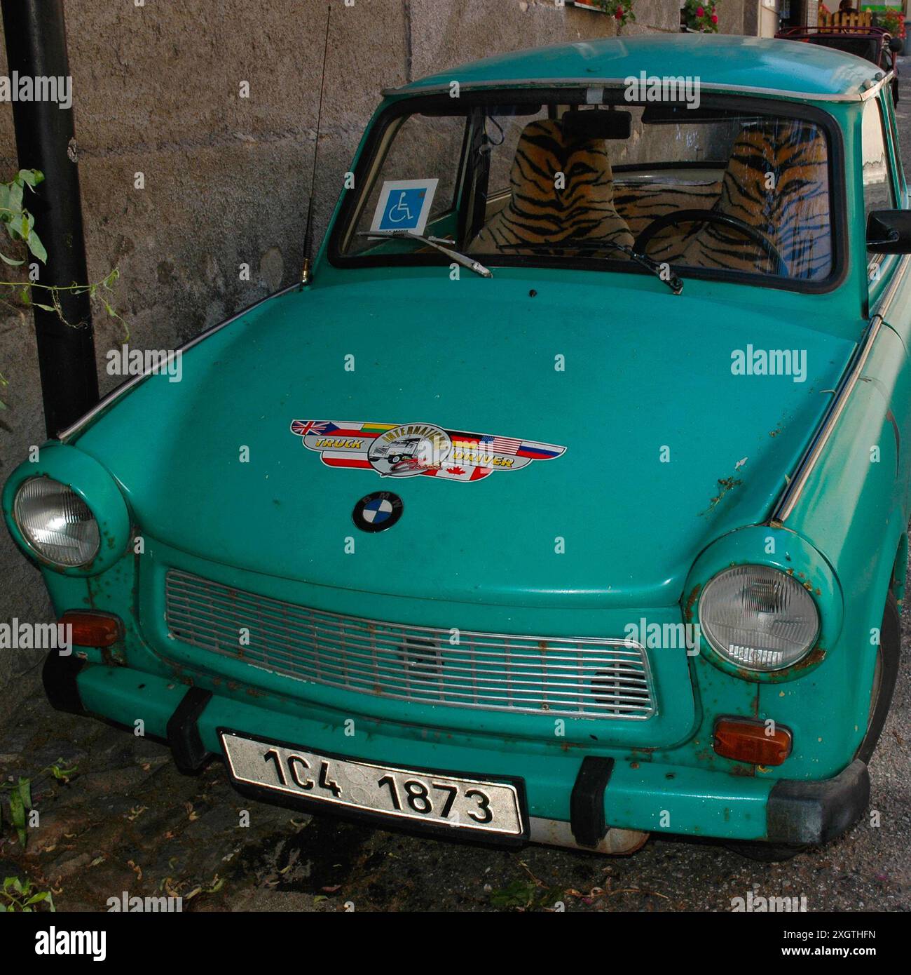 Rostgrüner Trabant mit Tigerfell-Tigerfellbezügen, die 2006 in Tábor, Südböhmen, Tschechien, geparkt wurden. Der Trabant, der 1957 auf den Markt kam, wird manchmal als „das schlechteste Auto aller Zeiten“ bezeichnet. Mit dem Fall der Berliner Mauer wurde es 1989 zu einem Kultfahrzeug in Deutschland. Dieser Trabant hat ein BMW-Logo und einen Aufkleber mit dem Aufdruck „International Truck Driver“ auf der Motorhaube oder der Motorhaube sowie einen Parkschein für Behinderte in der Windschutzscheibe. Stockfoto