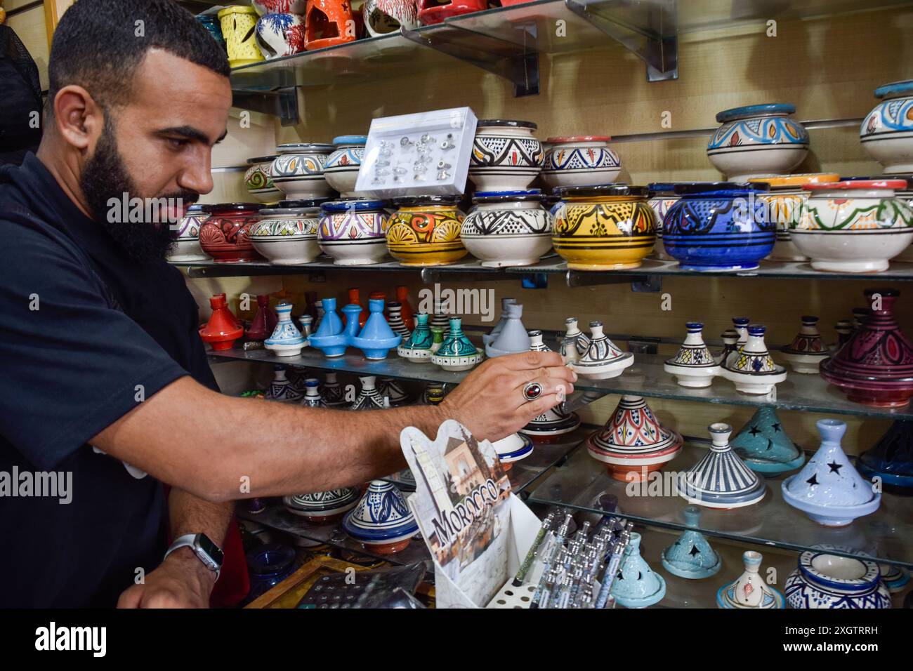Lokaler Verkäufer im Marrakesch-Souk, der farbenfrohe Kerzen in seinem Souvenirshop präsentiert. Marokko Stockfoto