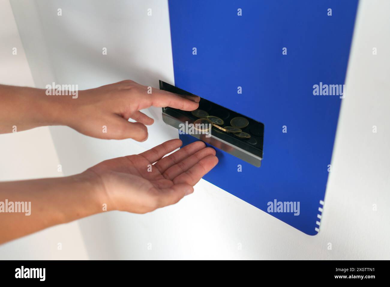 Frauenhände sammeln Münzen an einem Geldwechselautomaten Stockfoto