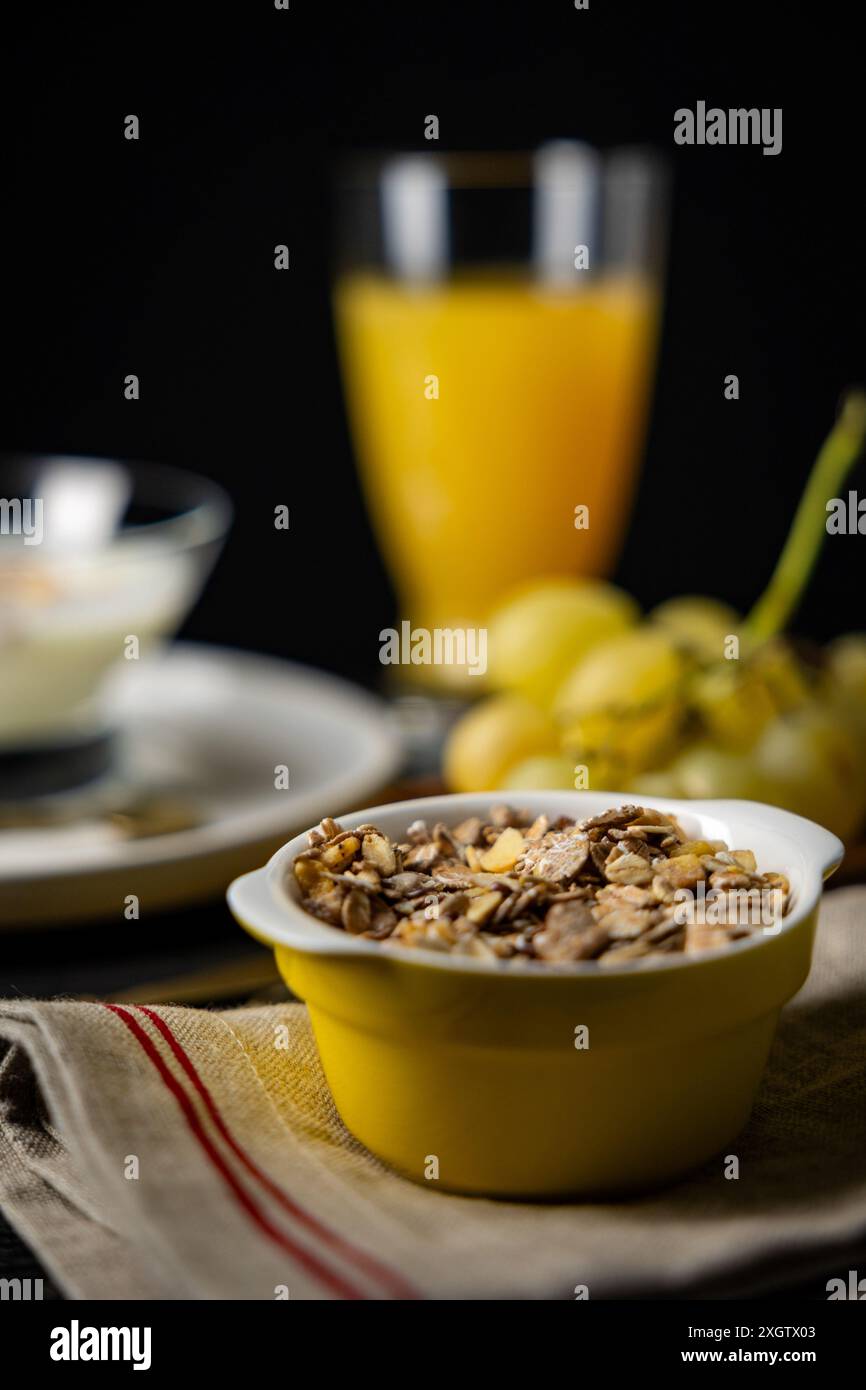 Studiofoto eines nahrhaften Frühstücks mit Orangensaft, Trauben und einer Schüssel Müsli, aufgenommen in einem scharfen Fokus im Vordergrund gegen eine Unschärfe Stockfoto