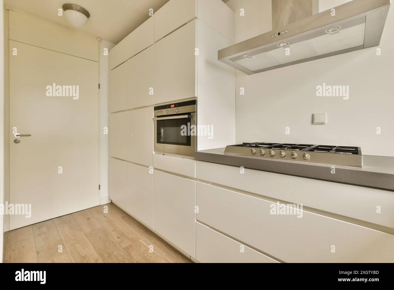 Eine makellose, moderne Küche mit weißen Schränken und einem Hartholzboden, komplett mit Edelstahlgeräten, befindet sich in Henkenshage, Amsterdam, Stockfoto