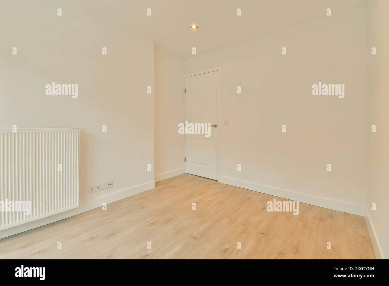 Ein leerer Raum mit weißen Wänden und Holzfußboden. Der Raum ist sauber und kann zur Lagerung genutzt werden Stockfoto