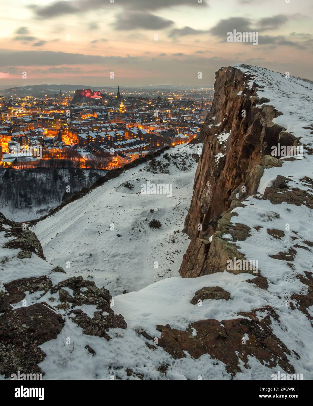 Vertikaler Blick auf Edinburgh, Schottland, mit Schnee bedeckt und mit Stadtlichtern an, von den Salisbury Crags im Holyrood Park an einem Wintermorgen Stockfoto