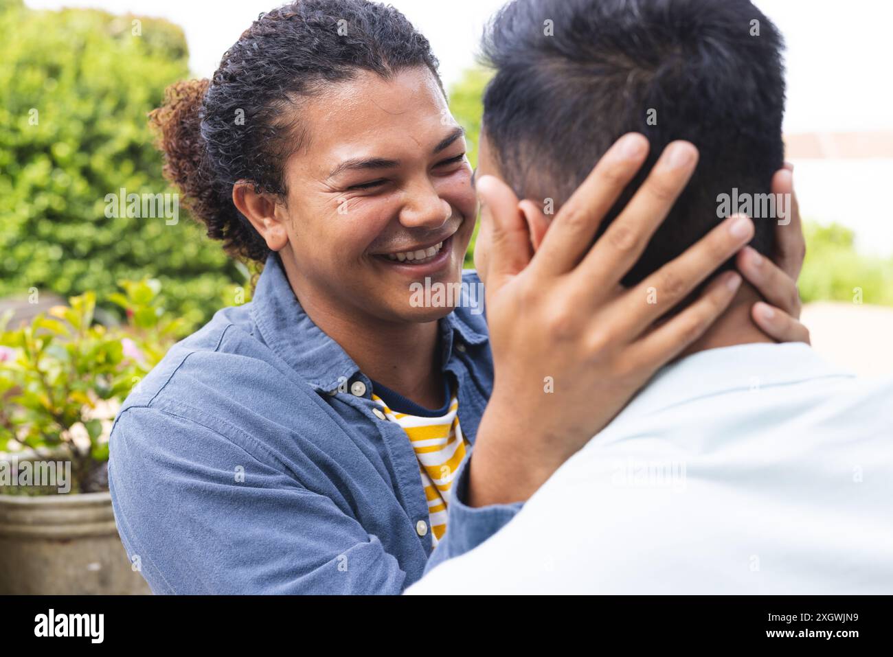 Ein junger birassischer Mann teilt einen zärtlichen Moment mit einem Mann aus dem Nahen Osten draußen. Ihre herzliche Interaktion unterstreicht ein starkes Band der Freundschaft oder Liebe. Stockfoto