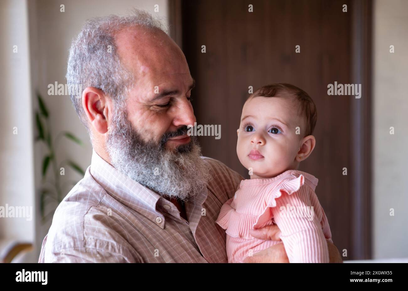 Opa und Enkelin halten sie im Wohnzimmer mit kawaii-Lächeln Stockfoto
