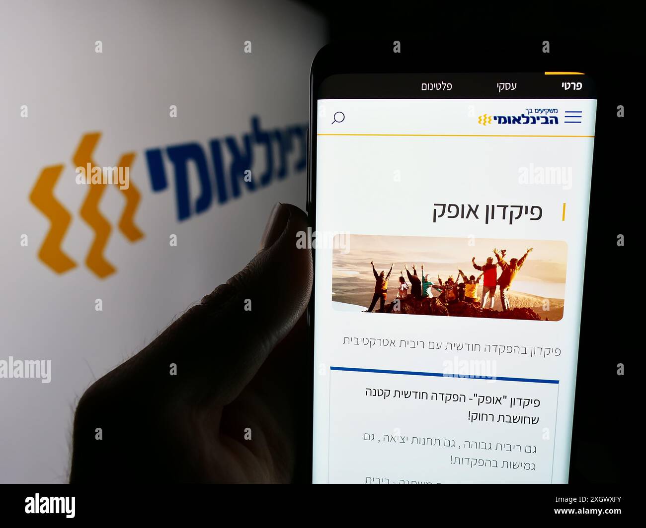 Person mit Smartphone und Webseite der Firma First International Bank of Israel Ltd. (FIBI) mit Logo. Konzentrieren Sie sich auf die Mitte des Telefondisplays. Stockfoto