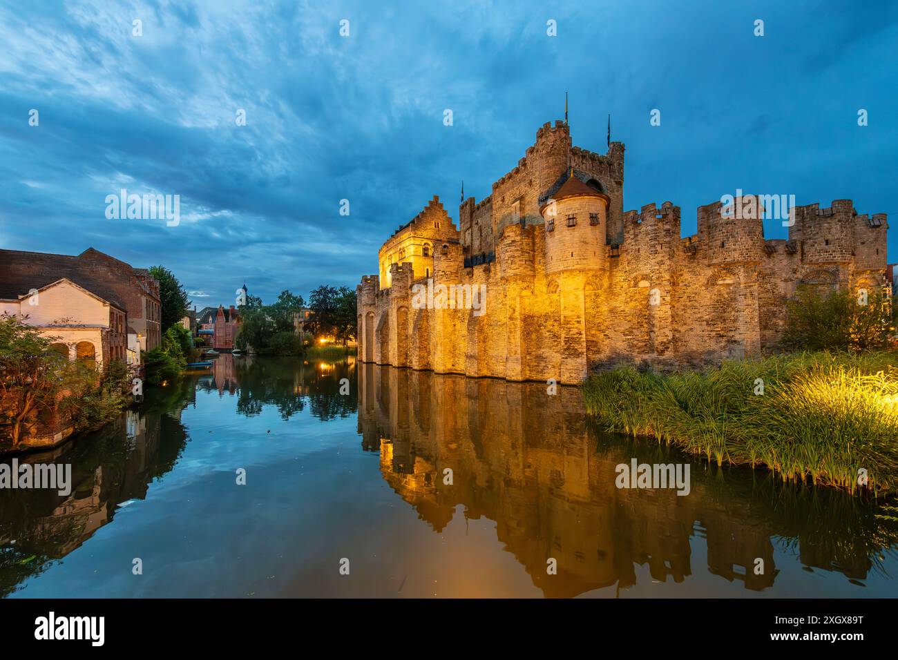 Abendlicher Blick auf ein beleuchtetes Schloss Gravensteen entlang der Leie in der historischen Altstadt von Gent, Belgien. Stockfoto