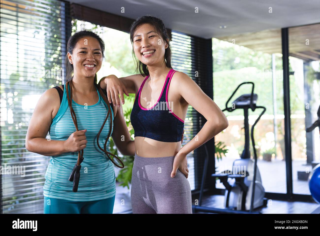 Porträt asiatischer Freundinnen, die Sportkleidung tragen und zu Hause ein Sprungseil halten. Fitness, Bewegung, häusliches Leben, Freundschaft, Aktivität und Leben Stockfoto