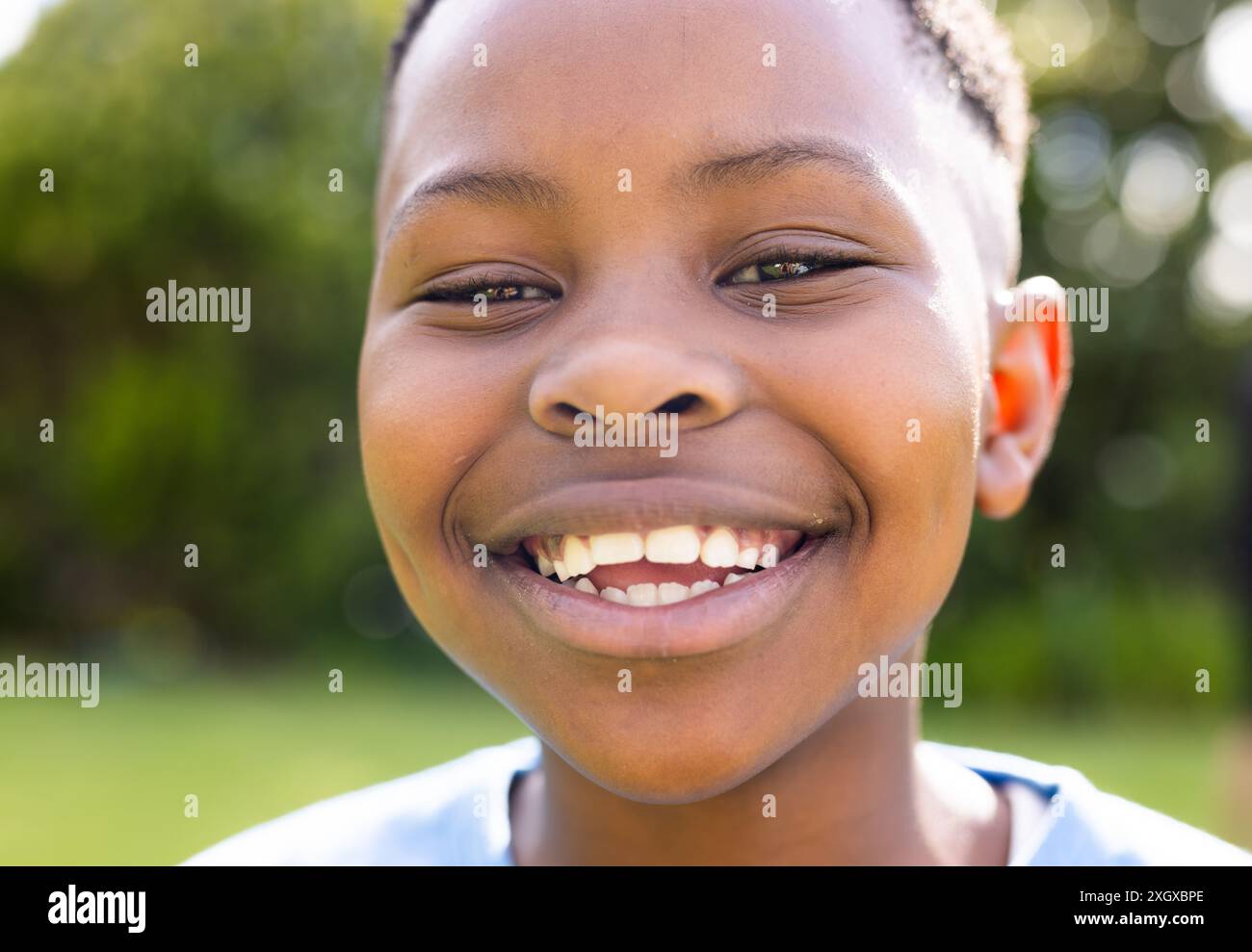 Der afroamerikanische Junge lächelt im Freien, unverfälscht. Sein fröhlicher Ausdruck fängt den unbeschwerten Geist der Kindheit ein. Stockfoto