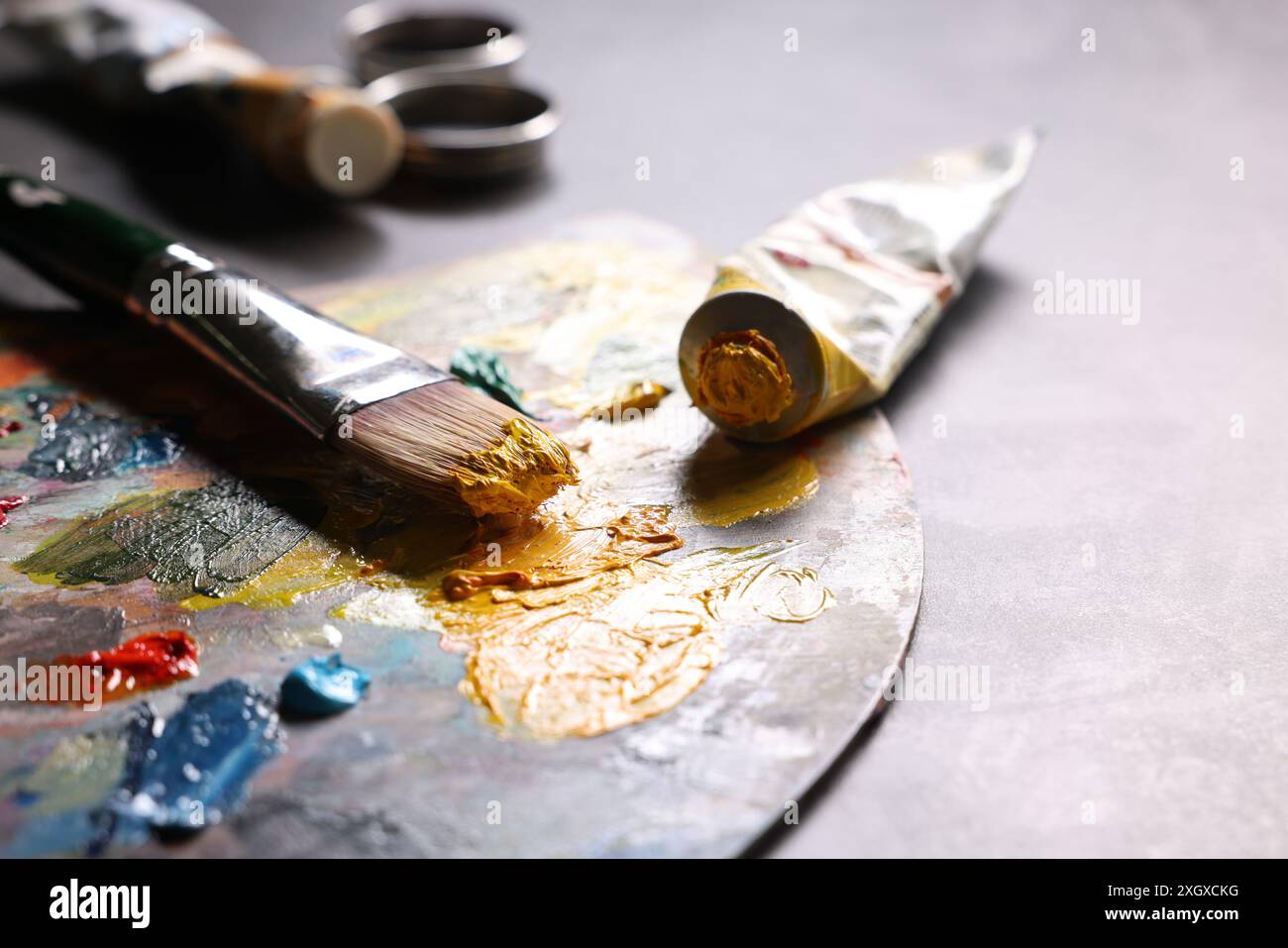 Künstlerpalette, Pinsel und Farben auf grauem Tisch, Nahaufnahme Stockfoto