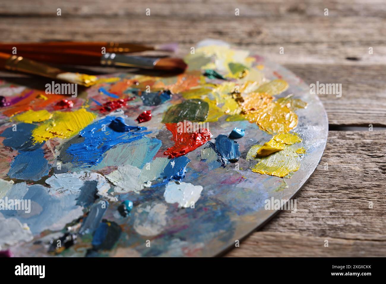 Künstlerpalette, Pinsel und Farben auf Holztisch, Nahaufnahme Stockfoto